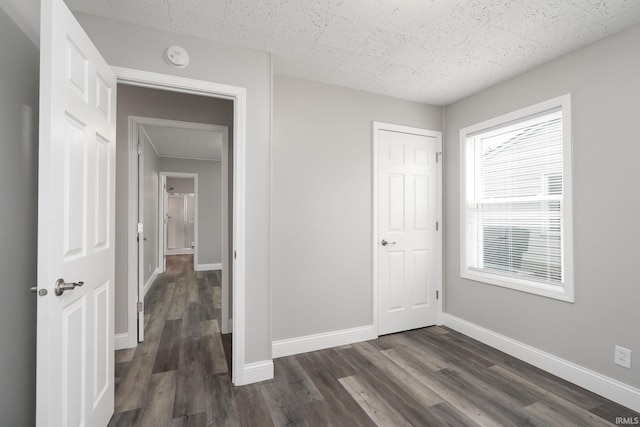 unfurnished bedroom featuring a closet, dark wood finished floors, and baseboards