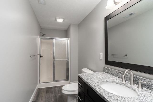 bathroom with toilet, a stall shower, visible vents, and wood finished floors