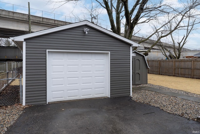 detached garage featuring driveway and fence