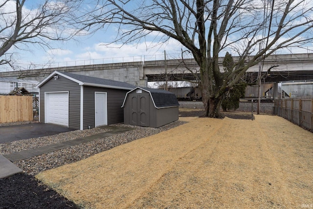 exterior space with a storage unit, fence, and aphalt driveway