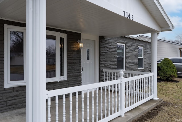 property entrance featuring stone siding and covered porch