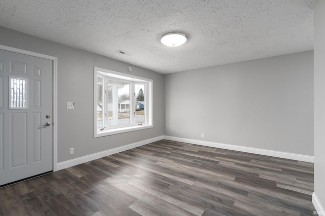 entryway featuring dark wood-style floors, a textured ceiling, visible vents, and baseboards