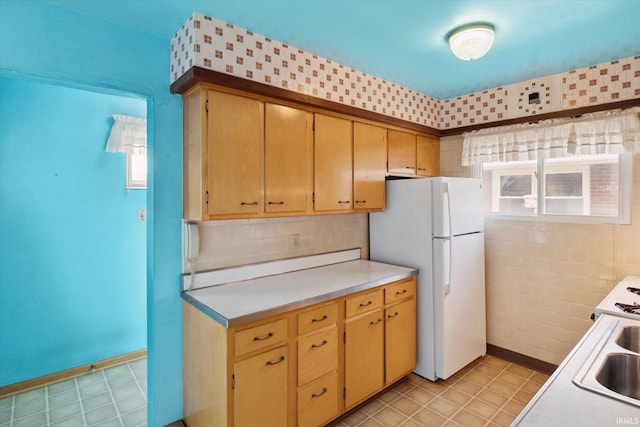 kitchen with freestanding refrigerator, light countertops, and backsplash