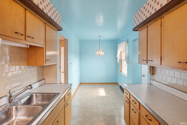 kitchen featuring baseboards, a sink, light countertops, pendant lighting, and backsplash