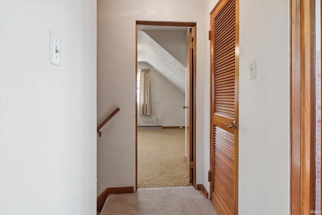 hallway with carpet flooring, an upstairs landing, and baseboards