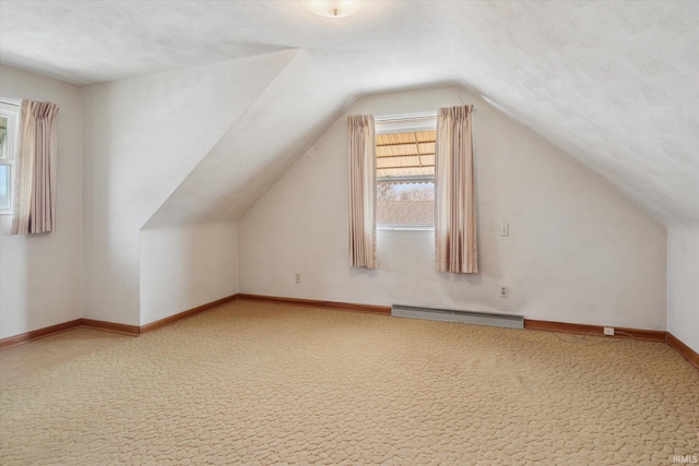 bonus room featuring a baseboard heating unit, vaulted ceiling, carpet, and baseboards