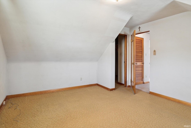 additional living space with light carpet, vaulted ceiling, and baseboards