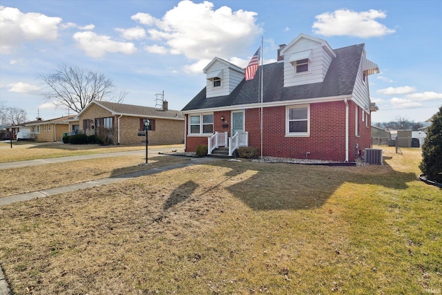 new england style home with a front yard and brick siding