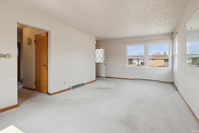 spare room featuring carpet, visible vents, baseboards, and a baseboard radiator