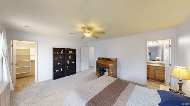 bedroom featuring a walk in closet, light colored carpet, visible vents, a ceiling fan, and baseboards