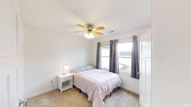 bedroom with light carpet, ceiling fan, visible vents, and baseboards