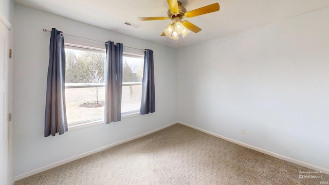 carpeted spare room with a ceiling fan, visible vents, and baseboards