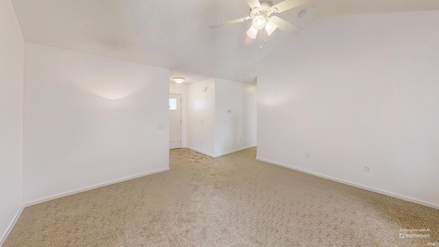 empty room with baseboards, vaulted ceiling, a ceiling fan, and light colored carpet