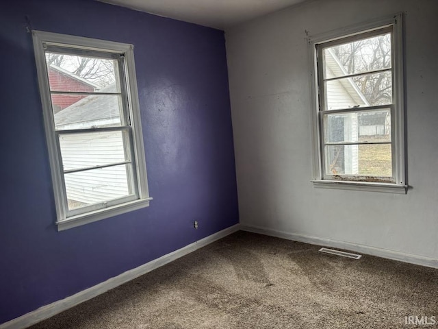 carpeted empty room with baseboards, visible vents, and a healthy amount of sunlight