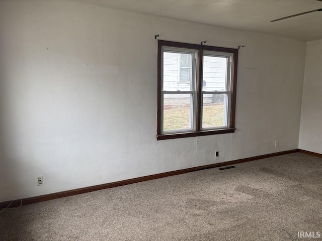 carpeted spare room with a ceiling fan, visible vents, and baseboards