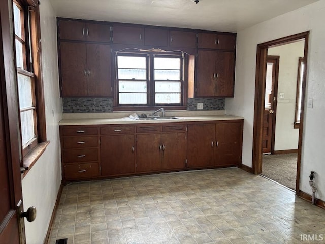 kitchen featuring light countertops, backsplash, a sink, and baseboards