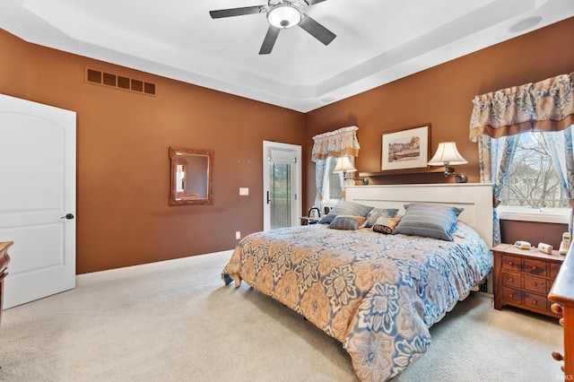 bedroom featuring a tray ceiling, visible vents, carpet, and multiple windows