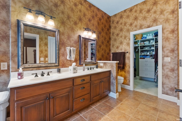 bathroom with toilet, wallpapered walls, and a sink