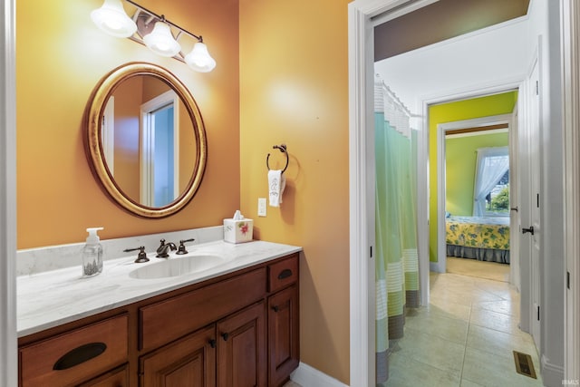 ensuite bathroom with tile patterned floors, baseboards, visible vents, and vanity