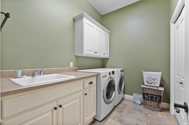 laundry room with a sink, baseboards, cabinet space, stone finish flooring, and washing machine and clothes dryer