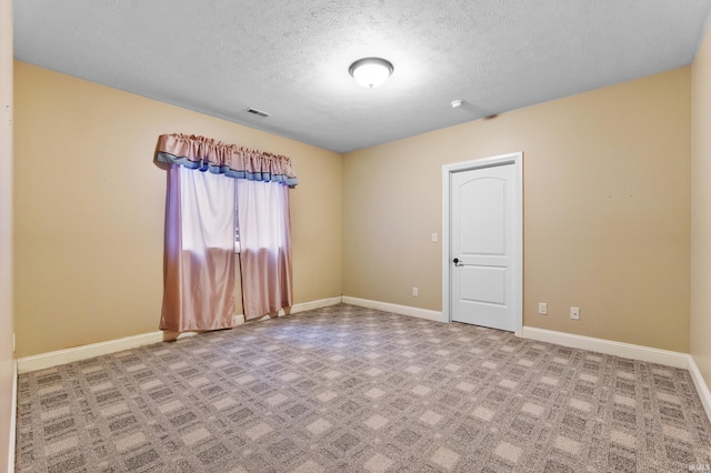 spare room featuring visible vents, baseboards, and a textured ceiling