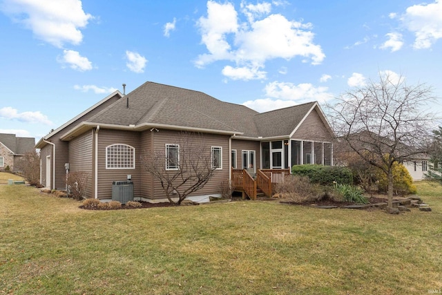 back of house featuring central air condition unit, a sunroom, roof with shingles, and a yard