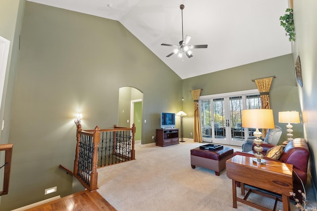 carpeted living room with arched walkways, high vaulted ceiling, a ceiling fan, baseboards, and french doors