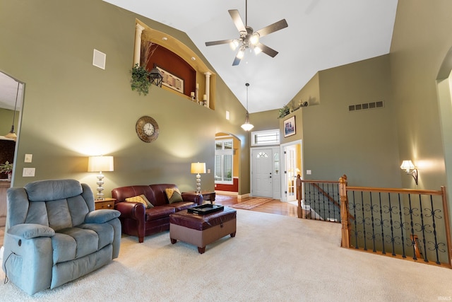 living area featuring arched walkways, carpet floors, ceiling fan, and visible vents