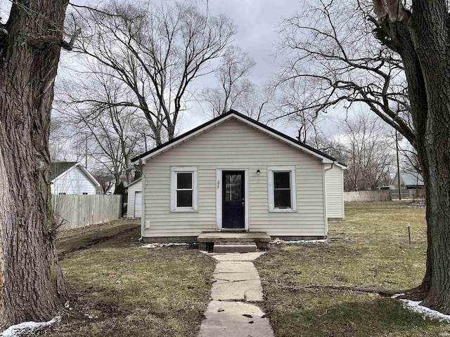 bungalow-style house with a front yard and fence