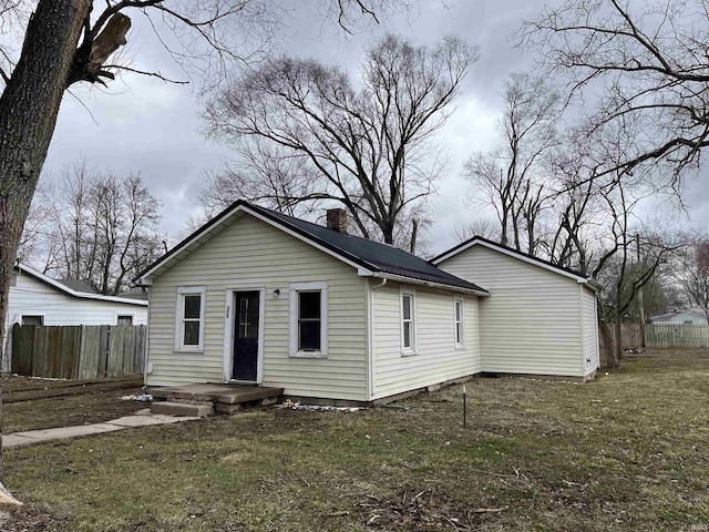 back of house with a chimney, fence, and a lawn