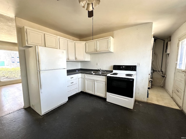 kitchen with electric range oven, dark countertops, freestanding refrigerator, white cabinetry, and a sink