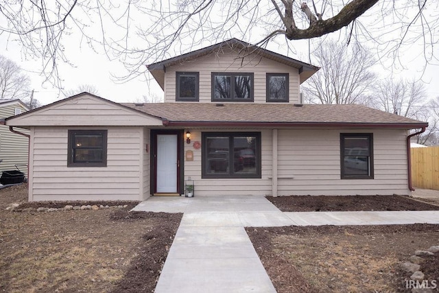 view of front of property with roof with shingles and fence