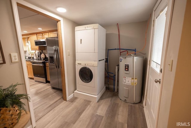 laundry area with electric water heater, light wood finished floors, and stacked washer and clothes dryer