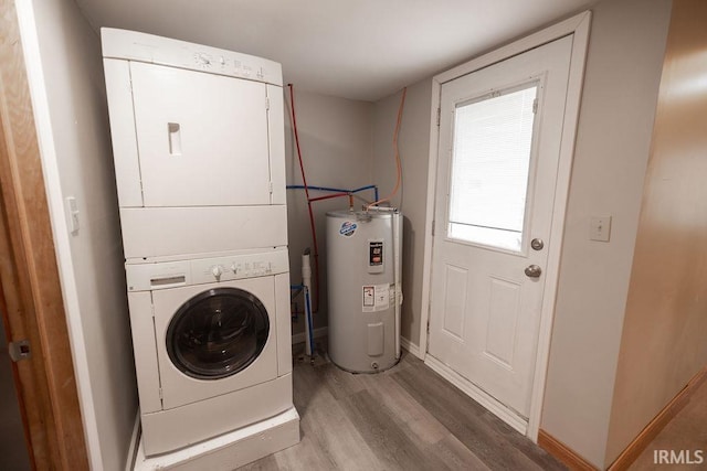 washroom featuring laundry area, baseboards, water heater, light wood-type flooring, and stacked washer and clothes dryer