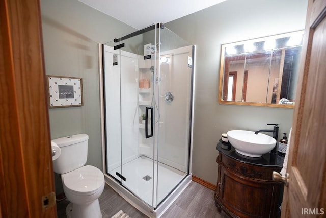 bathroom featuring wood finished floors, a stall shower, vanity, and toilet