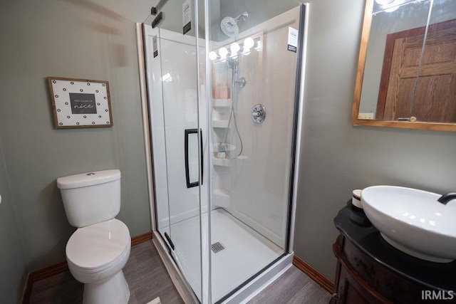 full bathroom featuring a stall shower, baseboards, toilet, wood finished floors, and vanity