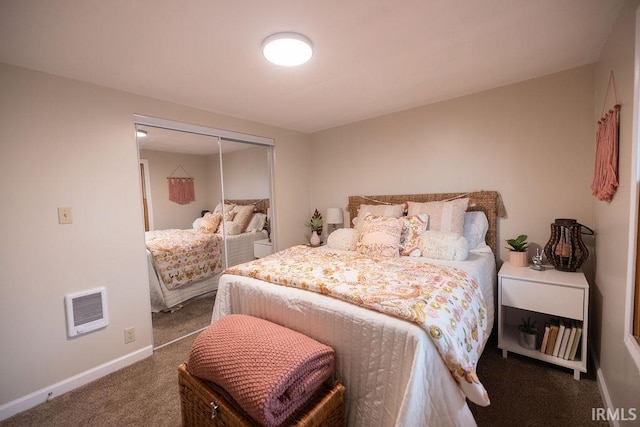 bedroom with heating unit, a closet, carpet flooring, and baseboards