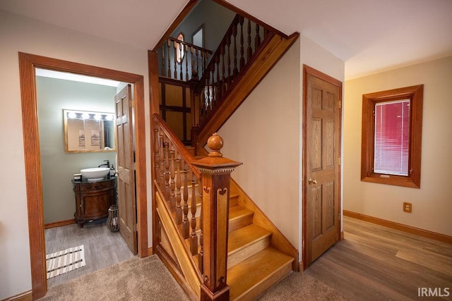 staircase featuring wood finished floors and baseboards