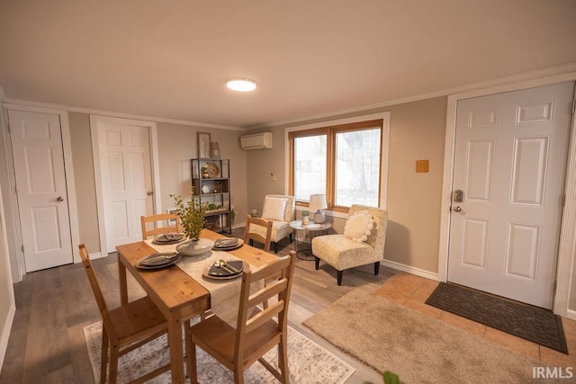 dining room featuring wood finished floors, crown molding, baseboards, and a wall mounted AC