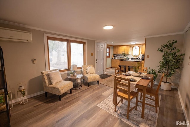 dining area featuring ornamental molding, baseboards, light wood finished floors, and a wall mounted AC