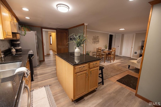 kitchen with light wood finished floors, crown molding, a breakfast bar, and electric stove