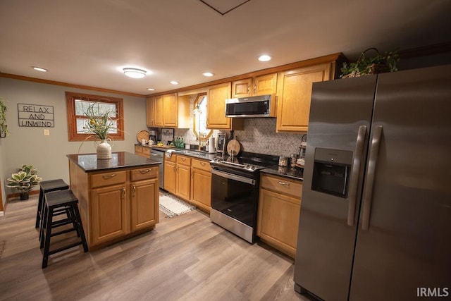 kitchen with a center island, dark countertops, light wood-style flooring, decorative backsplash, and appliances with stainless steel finishes