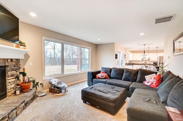 living room featuring a stone fireplace, recessed lighting, visible vents, baseboards, and carpet