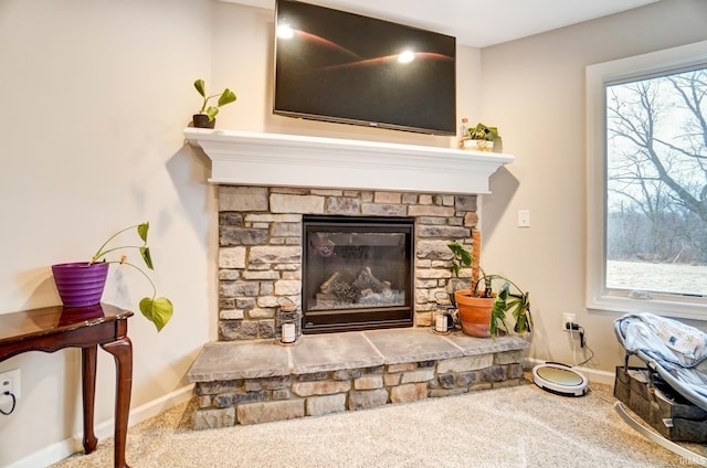 details with baseboards, carpet flooring, and a stone fireplace