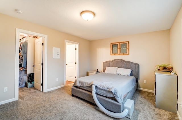 carpeted bedroom featuring baseboards and a walk in closet