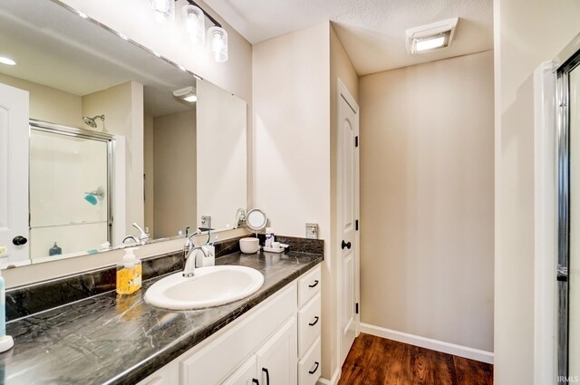 bathroom featuring a stall shower, baseboards, wood finished floors, and vanity