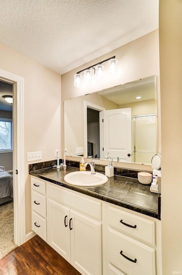 ensuite bathroom featuring connected bathroom, a textured ceiling, wood finished floors, and vanity