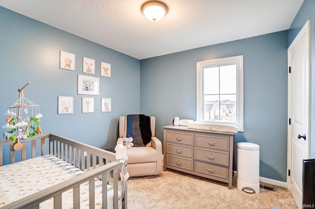 bedroom with a nursery area, baseboards, and light colored carpet