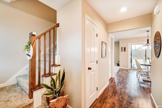 hall with a notable chandelier, stairs, baseboards, and dark wood-style flooring