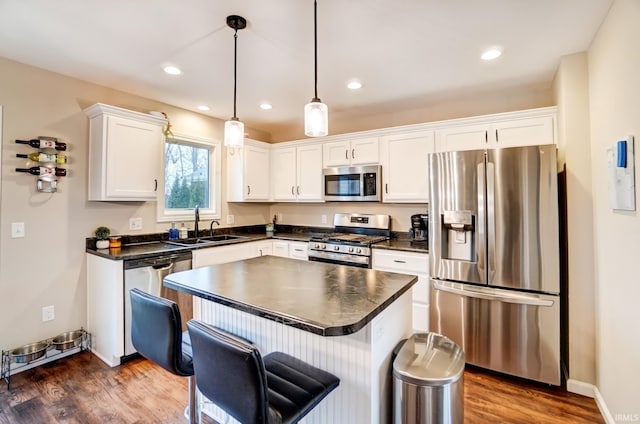 kitchen featuring white cabinets, dark countertops, dark wood-style floors, appliances with stainless steel finishes, and a sink